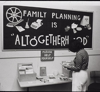 A woman peruses a table of family planning literature. (National Library of Medicine)